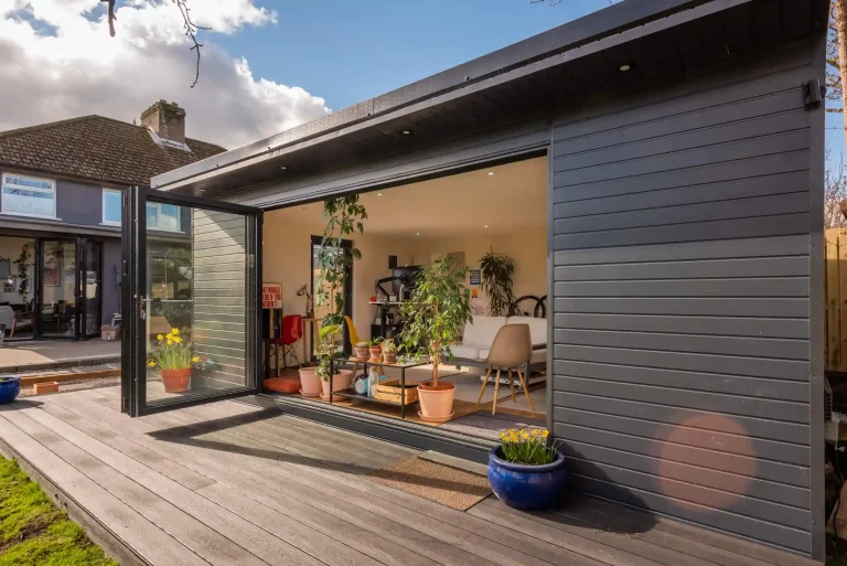 Grey garden room with open bi-fold doors and a composite deck