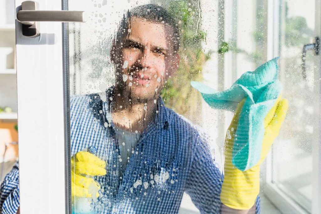Person cleaning the glass doors of a garden room with a cloth